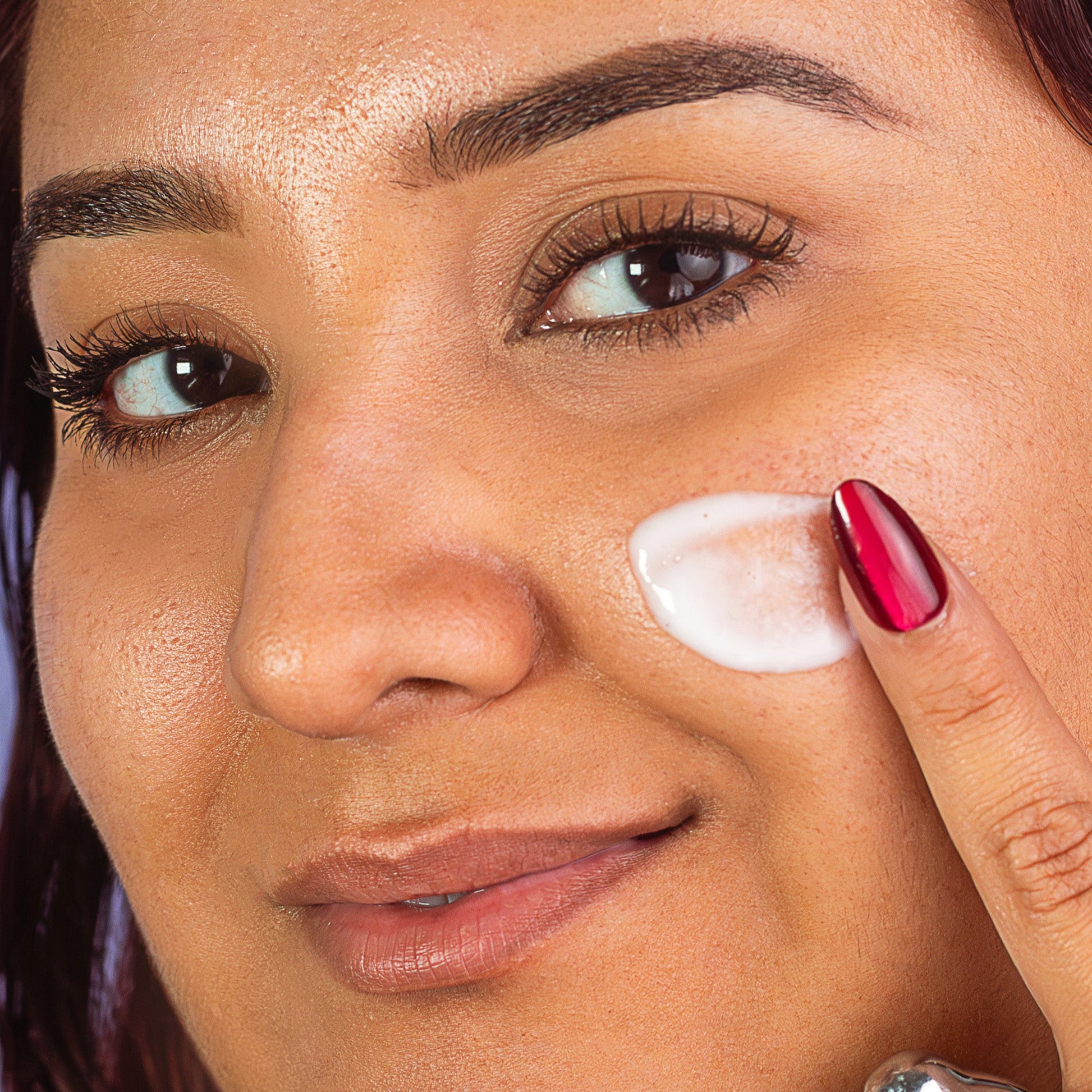 Woman applying blurr. smooth and bond primer to her face with a close-up view.