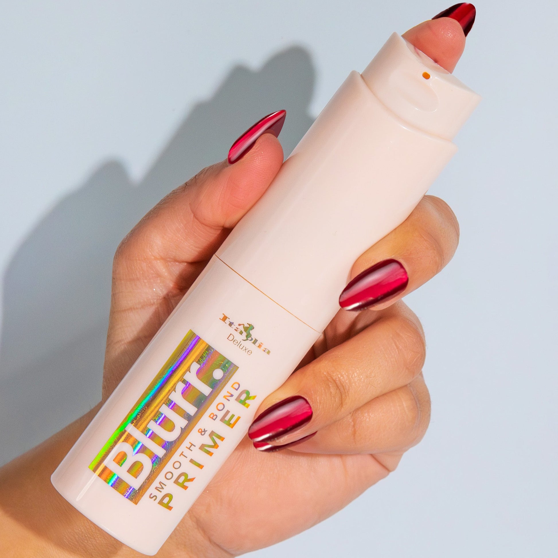 Hand holding the Blurr. Smooth & Bond Primer with colorful text against a light blue background